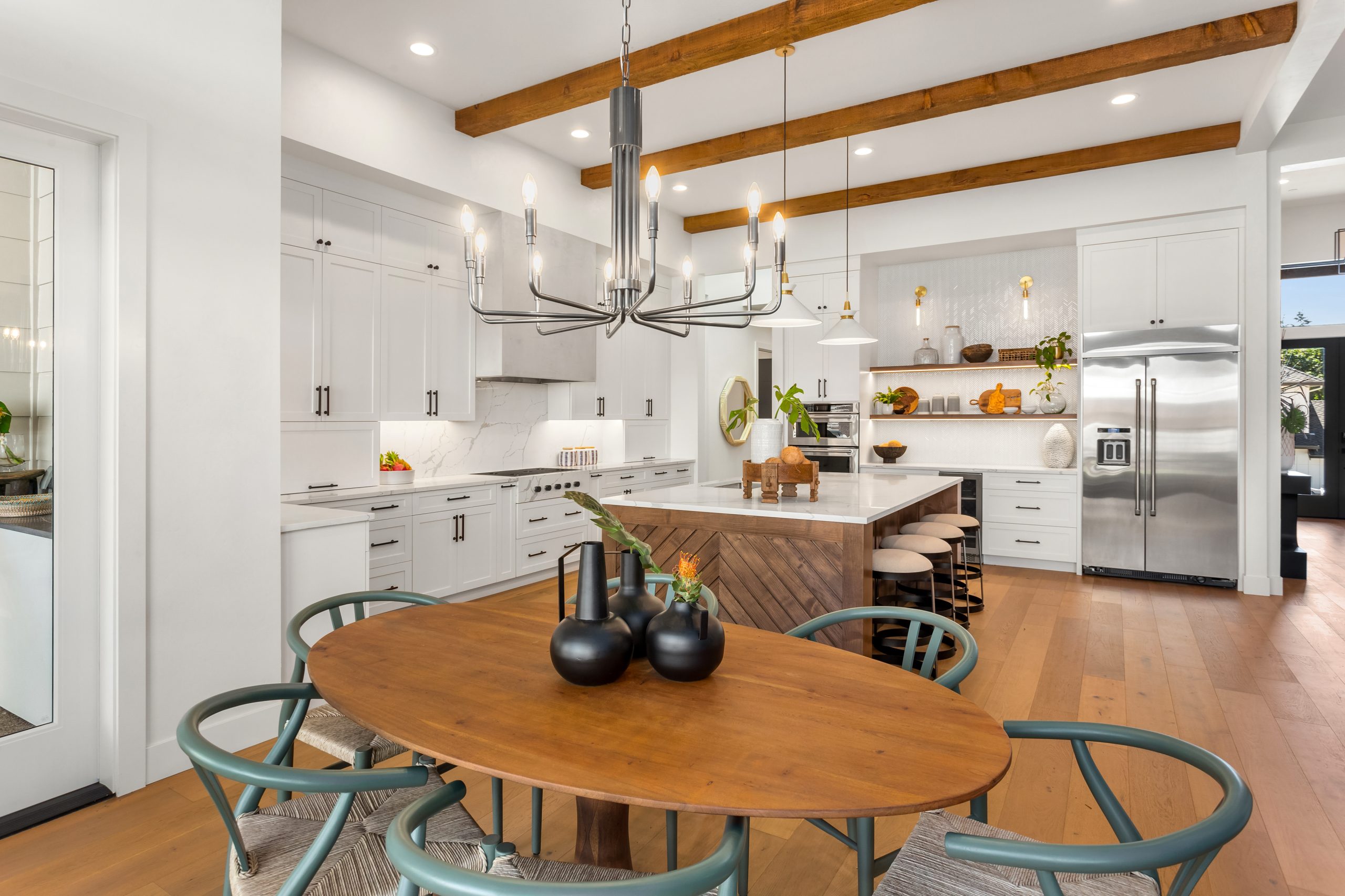 beautiful kitchen and dining room in new luxury home with island, pendant lights, and hardwood floors.