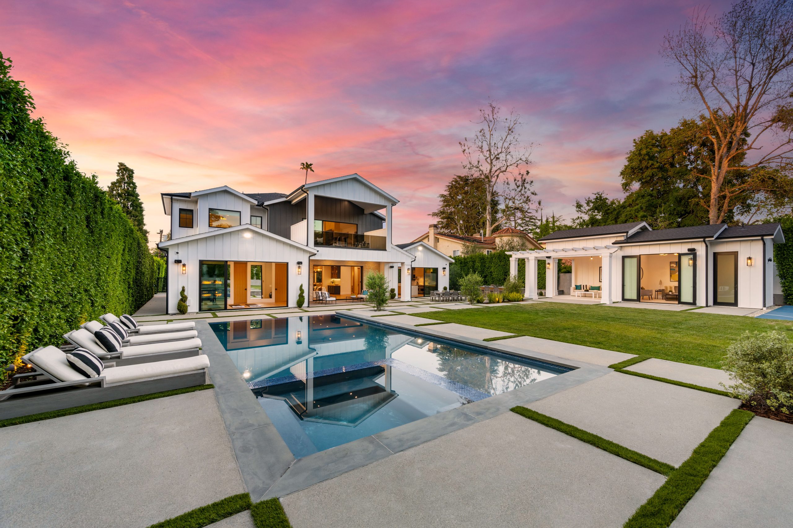 a beautiful swimming pool in front of a large house with a lot of green trees